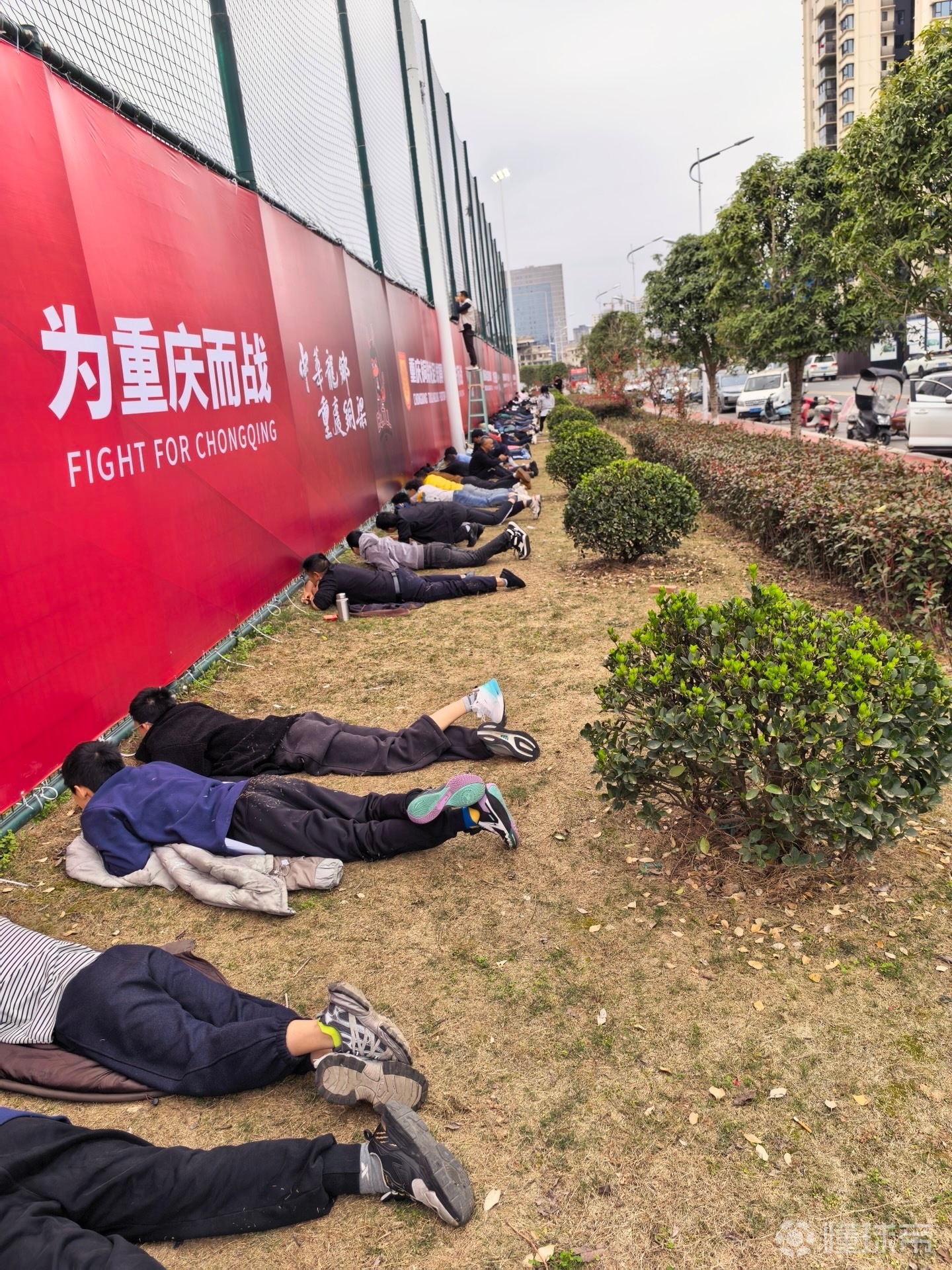 接地气，重庆球迷趴在草地上透过围栏缝隙观看铜梁龙热身赛